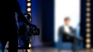 Blurred out man hosting a show representing the Frank Speech settlement.