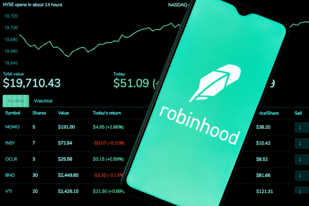 The Robinhood logo is seen on a cellphone with a stock chart behind it representing the Robinhood class action lawsuit settlement.