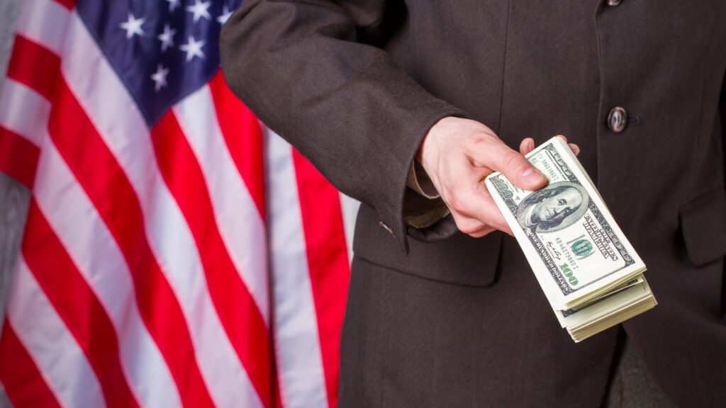 Governemnt man handing over money in front of U.S. Flag