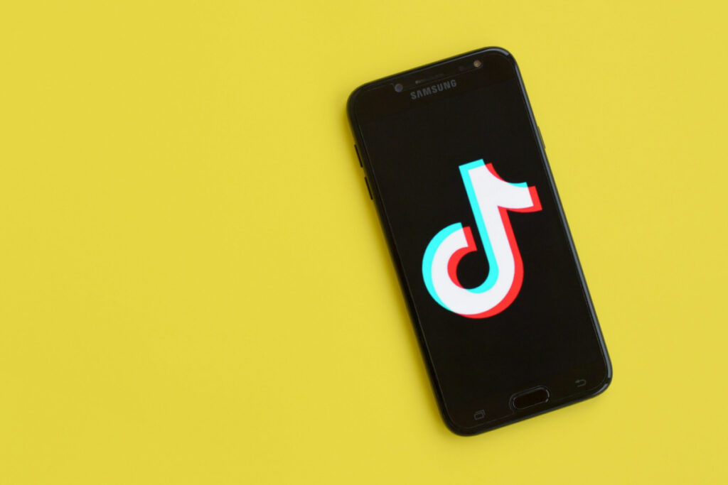 TikTok logo on cell phone and yellow background