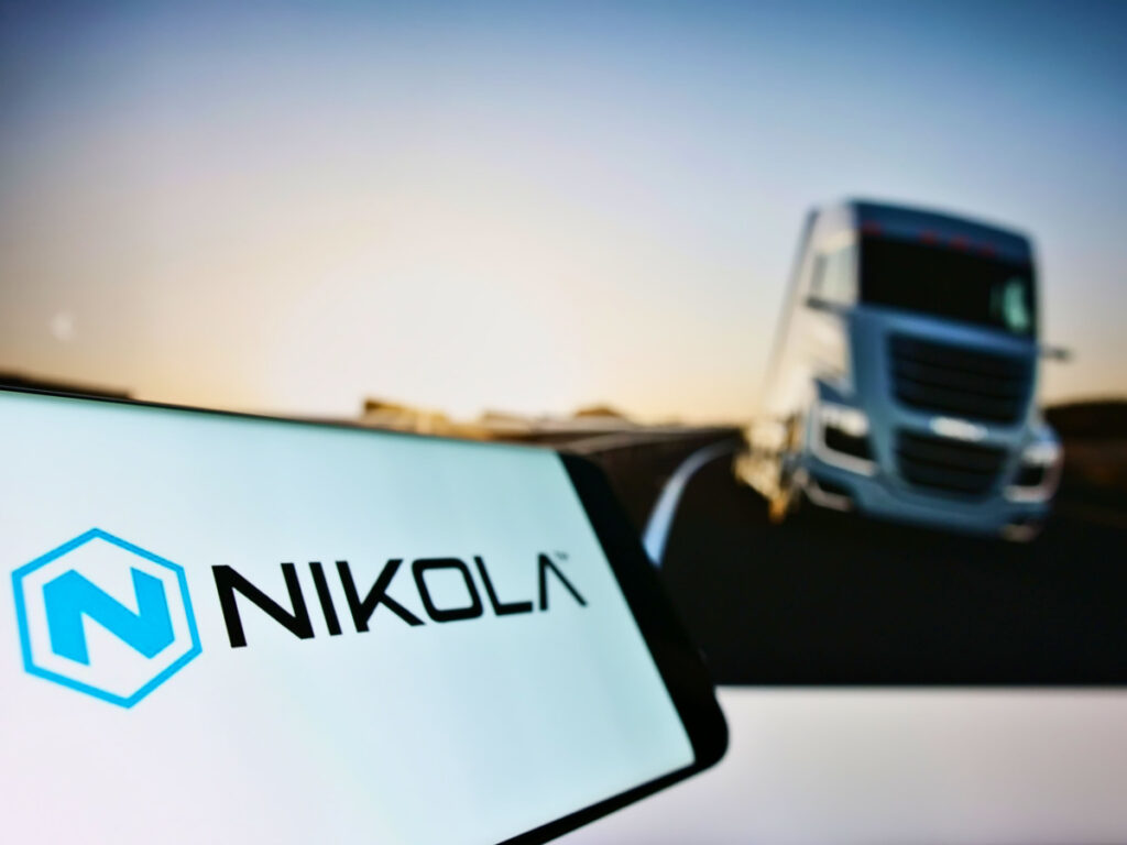 Nikola logo on cell phone next to Nikola semi truck