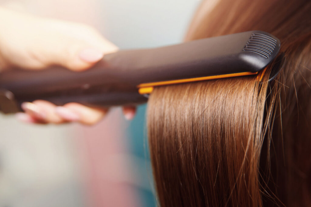Close up shot of hair being straightened with an iron