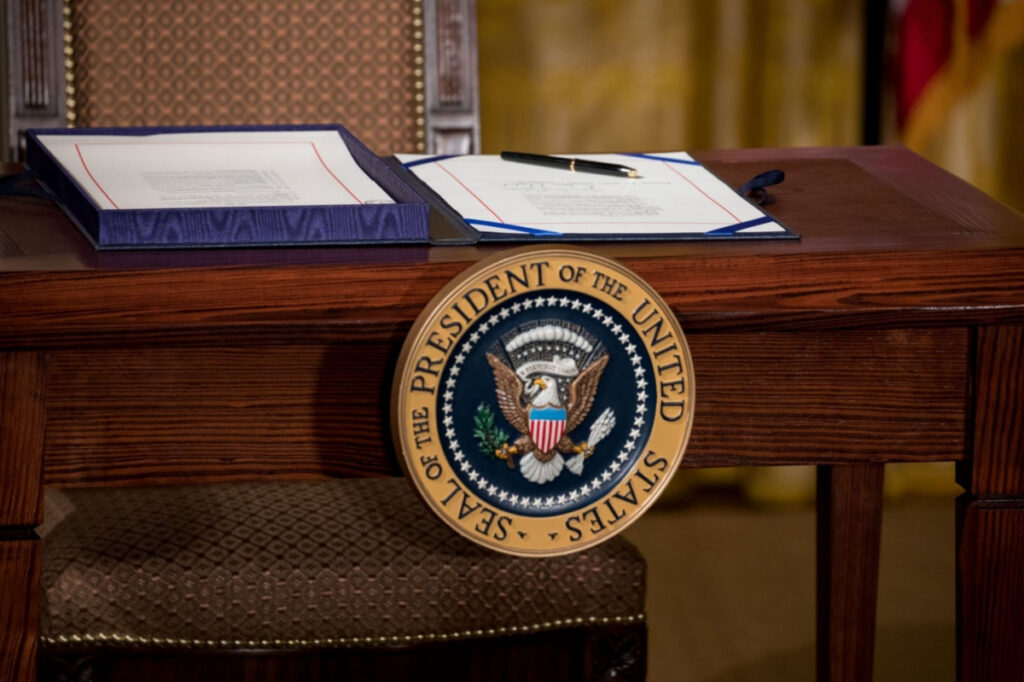 The Presidential Seal on a desk, representing President Biden limiting government use of commercial surveillance software