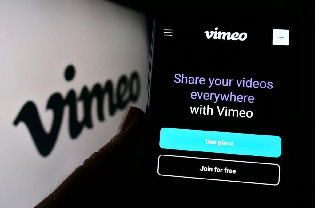 Vimeo logo on a white background next to a cellphone with Vimeo's webpage on it, representing the Vimeo subscriptions class action