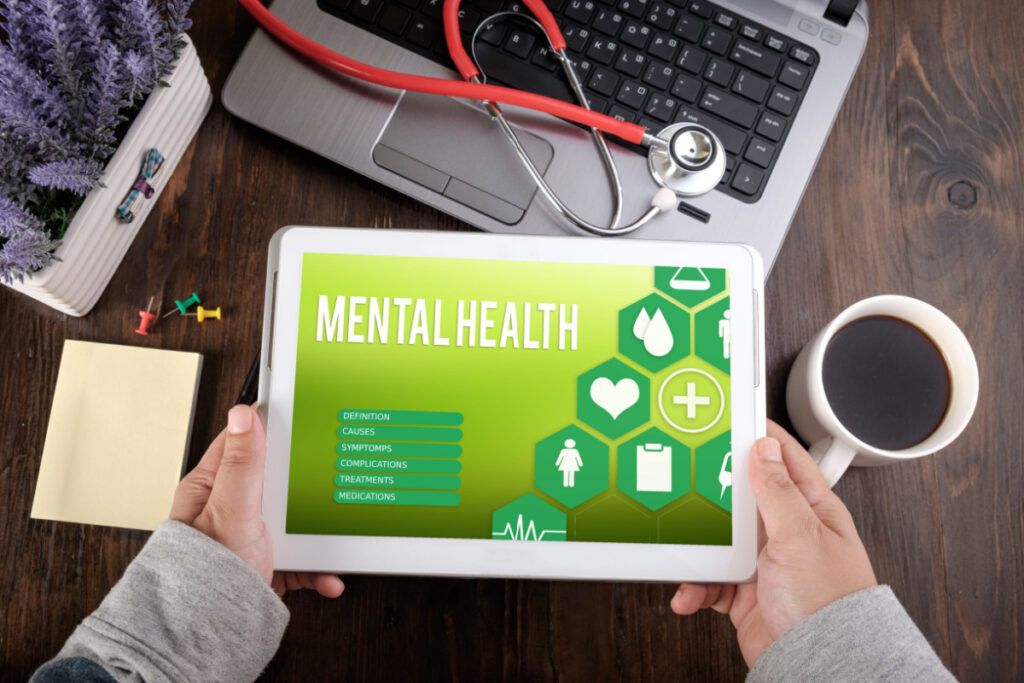 Someone holding a tablet that reads "mental health"