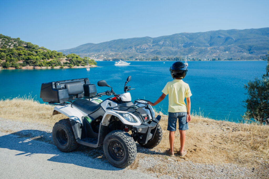 Little boy riding and looking quad bike on Greece island.