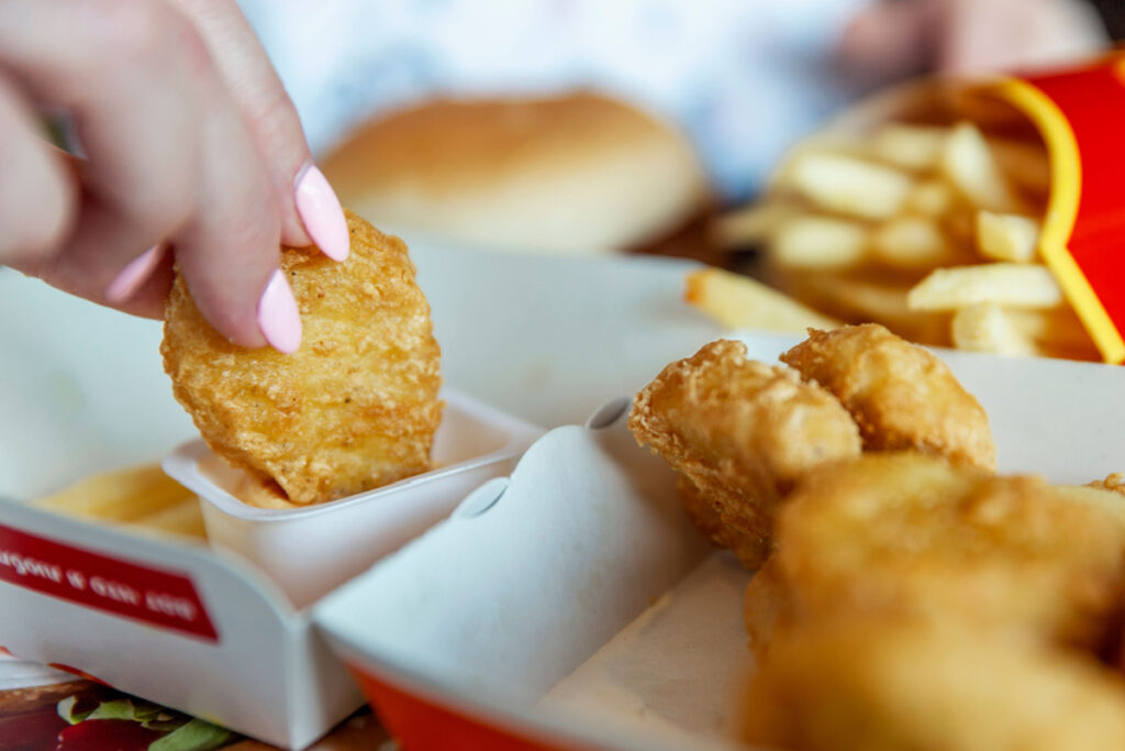 A woman eats chicken nuggets at McDonald's, representing the McNugget burn lawsuit.