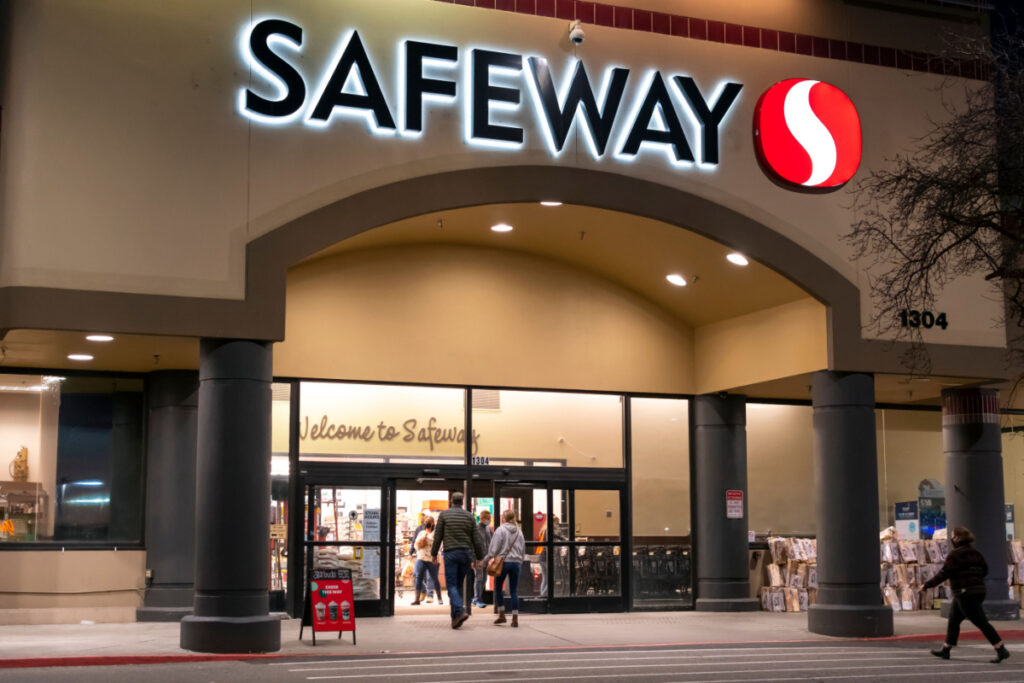 Shoppers enter an illuminated Safeway Supermarket Grocery store representing the Oregon Safeway surcharge class action lawsuit settlement.