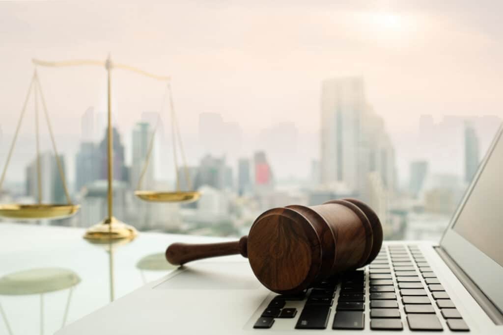 law legal technology concept. judge gavel on computer with scales of justice on desk of lawyer.