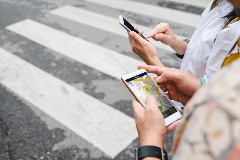 Two people use maps their smartphones while standing on a city street, representing the Meta Platforms location privacy settlement.