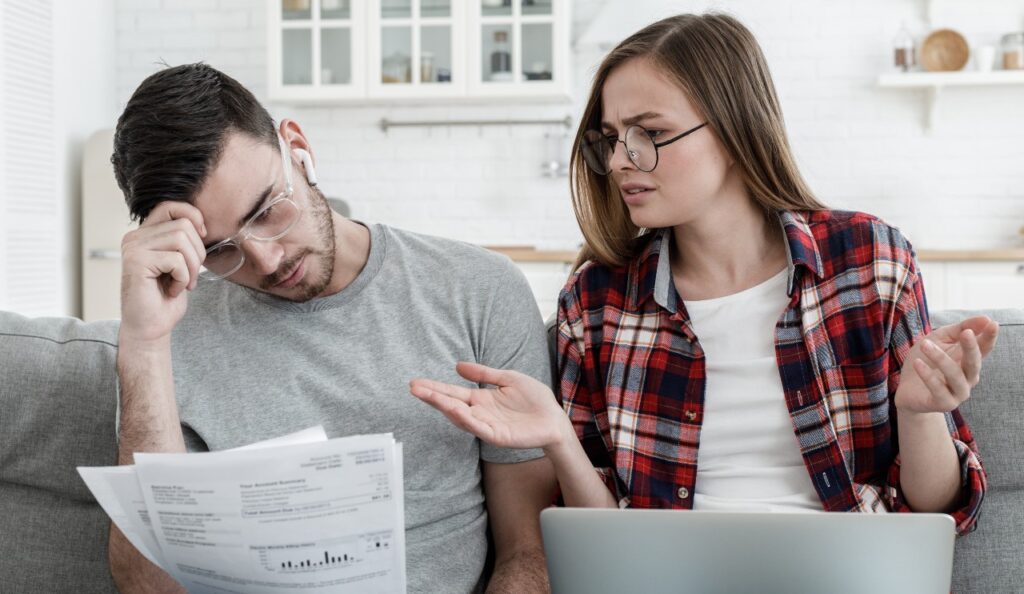 wife and husband checking details of bills trying to understand why fees are so high.