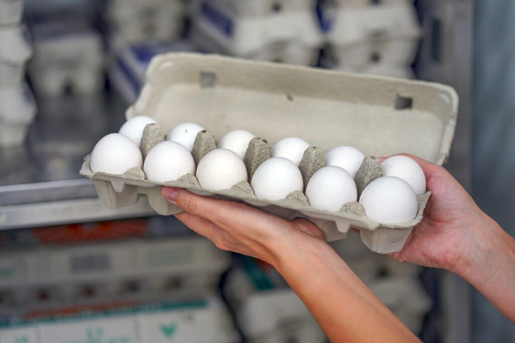 Close up of a person holding eggs in a grocery store.