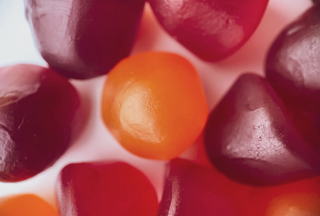 Close-up texture of red, orange and purple melatonin gummies.