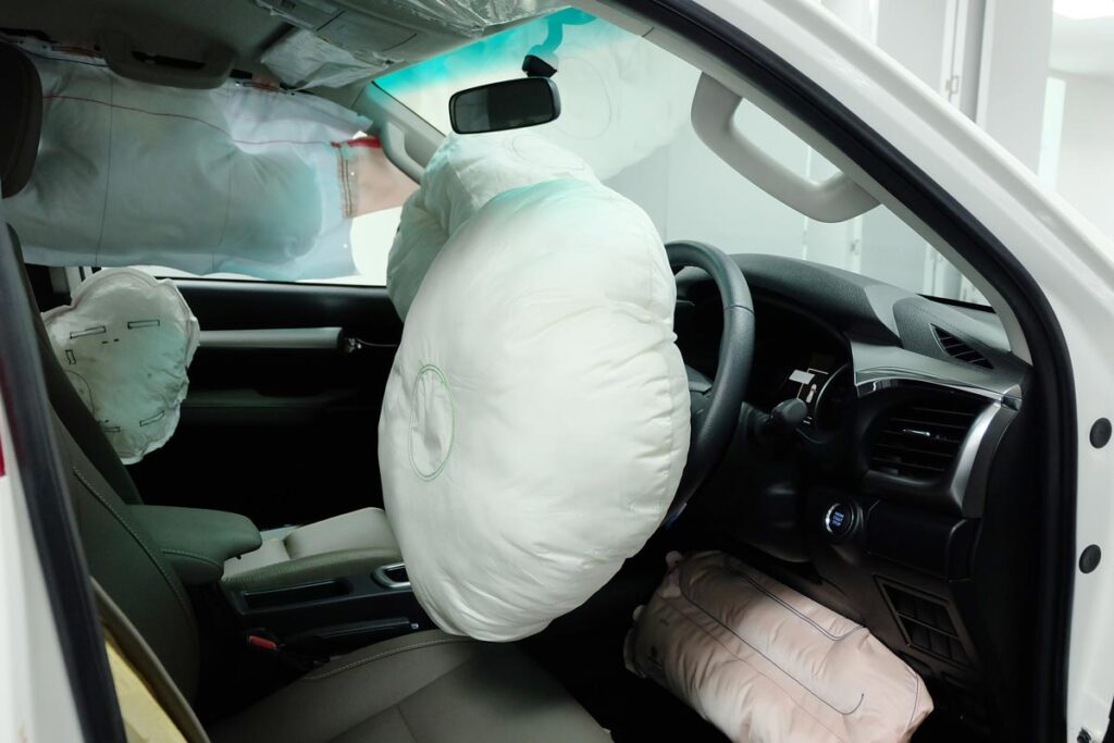 Interior of a wrecked vehicle with inflated airbags, representing defective airbag inflators. 