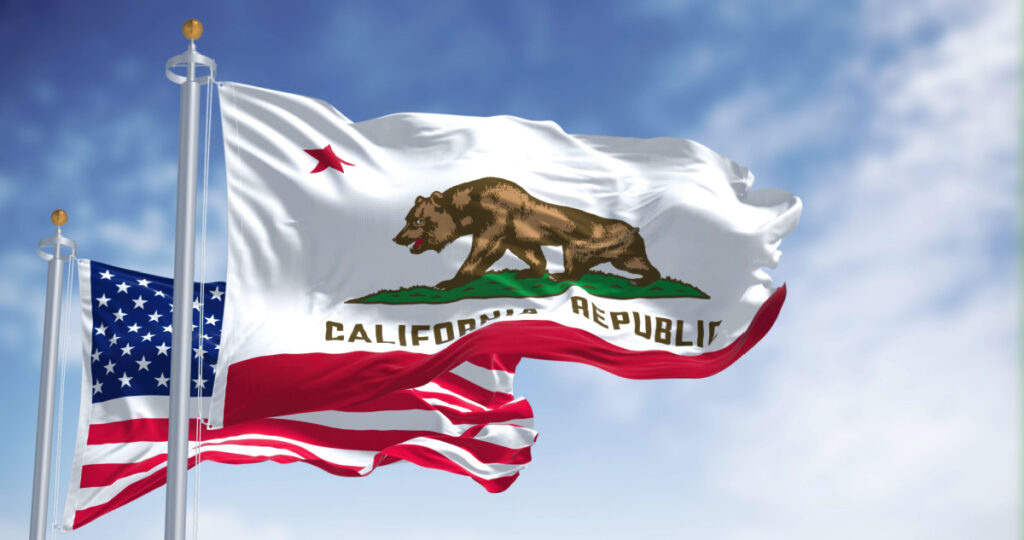 The California state flag flying along with the national flag of the United States of America, representing the state's recommended reparations for descendants of slavery.