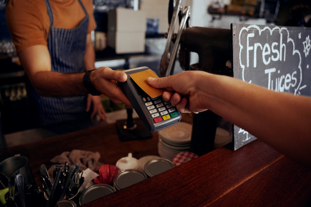 Close up of a coffee house employee taking a credit card payment, representing the proposed Credit Card Act.