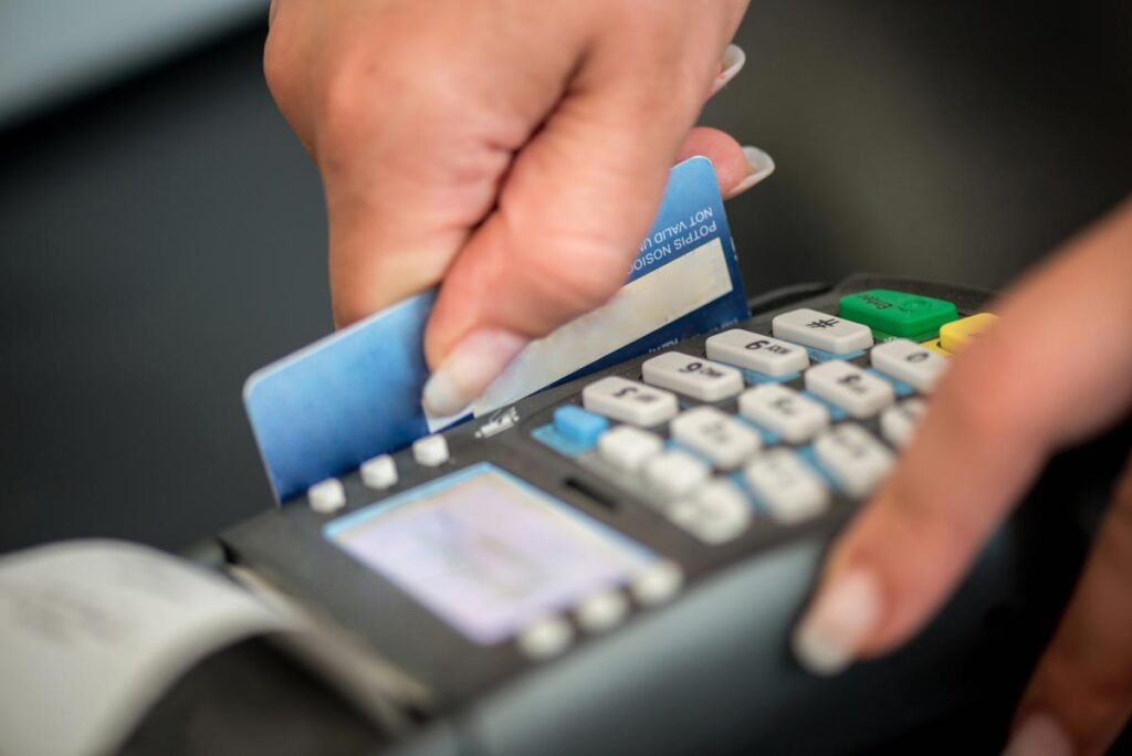 Close up of a person swiping a debit card, representing the Redstone Federal Credit Union fees settlement.
