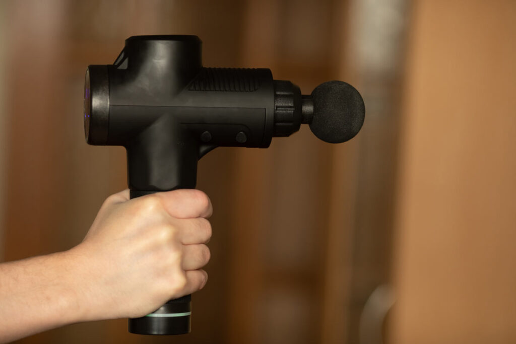 Close up of a hand holding a body massage gun, representing the Amazon/Therabody lawsuit.