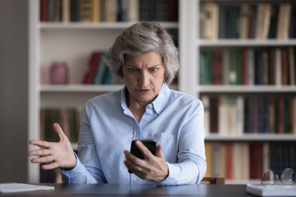 An angry old lady looking at her phone, representing the FTC’s settlement with auto warranty scam operators.