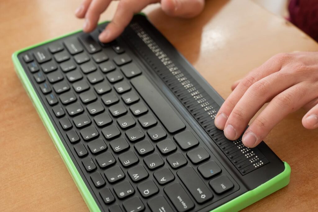 Close up of a blind mans hands using an accessibility keyboard, representing the Panama Jack website class action.