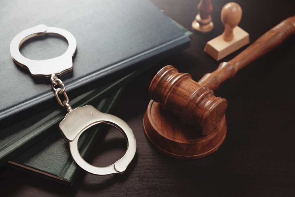 A judges gavel and handcuffs on a law book, representing the COVID relief funds scam charges.