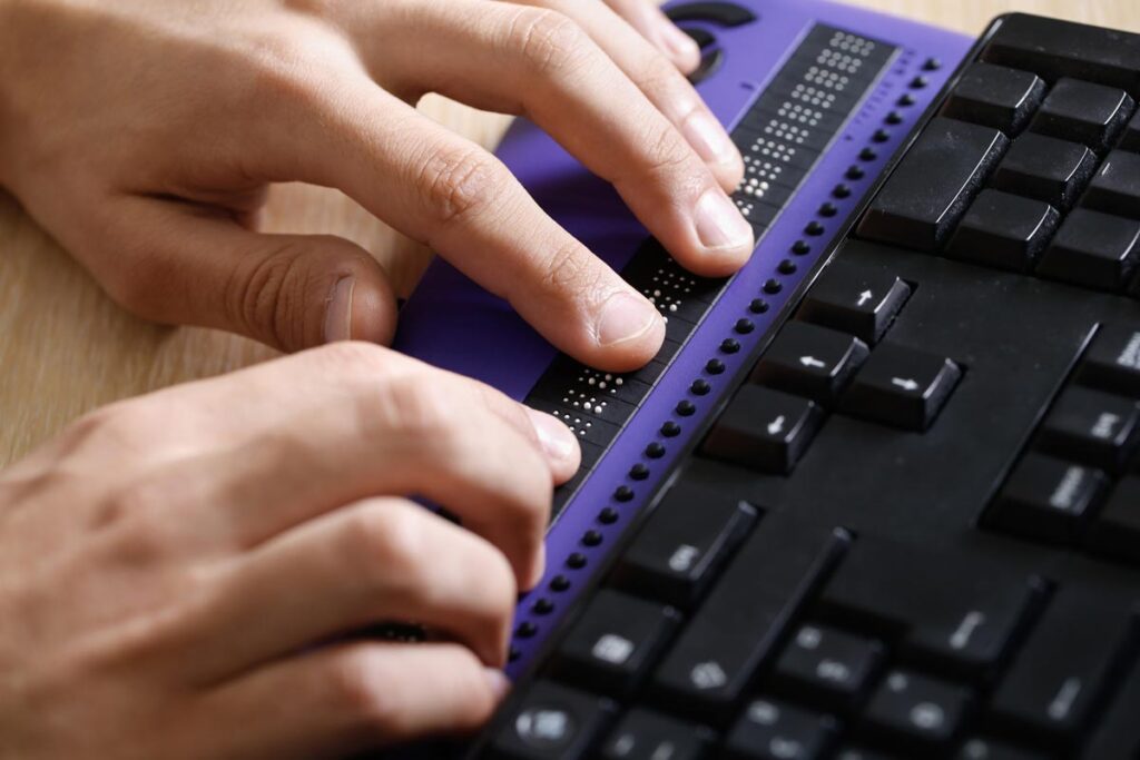 Close up of a persons hands typing on a braille keyboard, representing the Northwestern University class action.