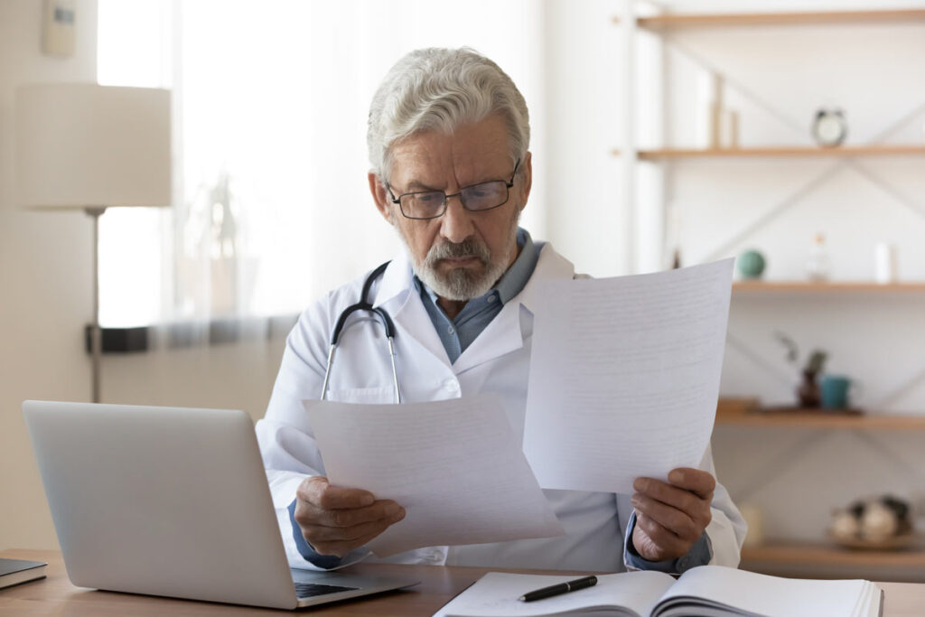 A concerned doctor looking at documents, representing the Memorial Health employment agreement contract class action settlement.
