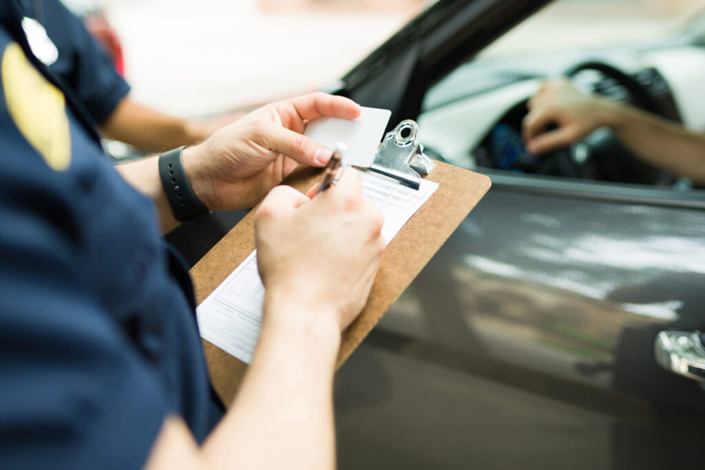 Close up of a cop writing a parking ticket, representing the New York City tractor parking class action lawsuit settlement.