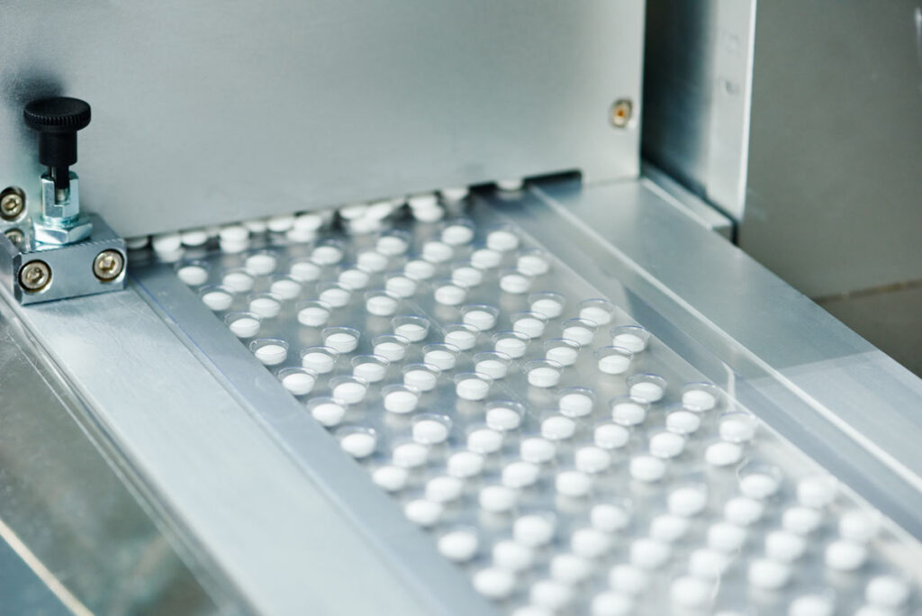 Close up of pills on a production machine, representing the Pfizer drugs supply disruptions.