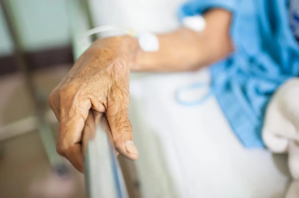 Close up of elderly woman's hand holding a bed railing, representing the nursing home bedsore verdict.