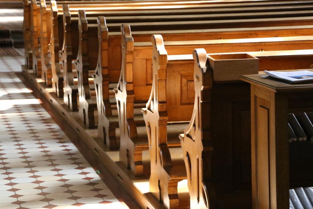 Close up of wooden benches inside a Catholic church, representing the Catholic sex abuse settlement.