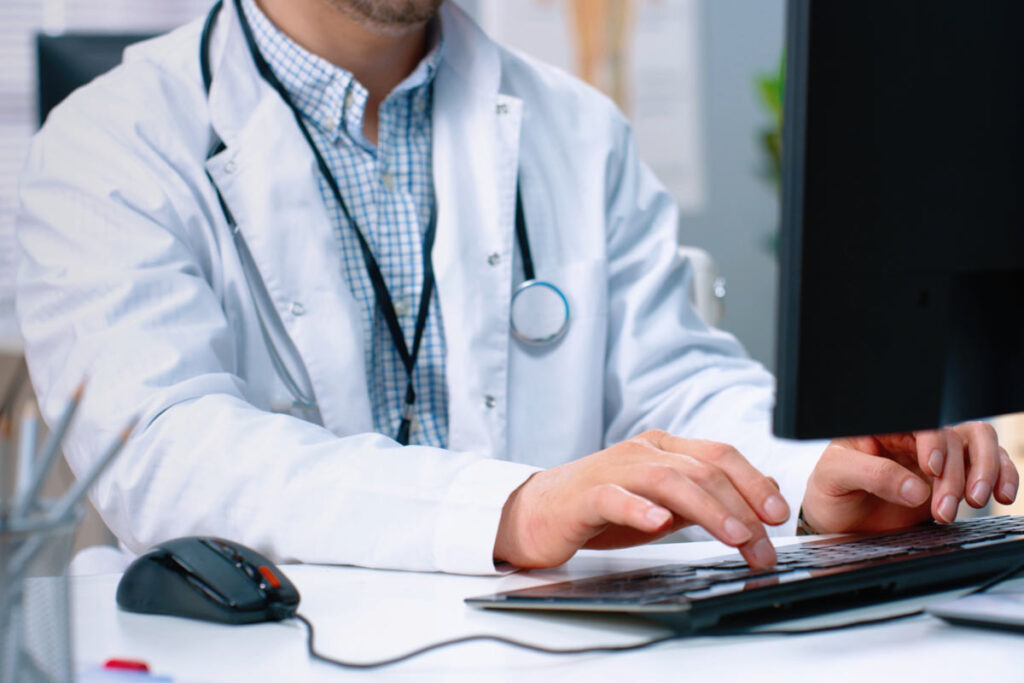Close up of a doctor typing on a computer, representing the Henry Ford data breach class action.