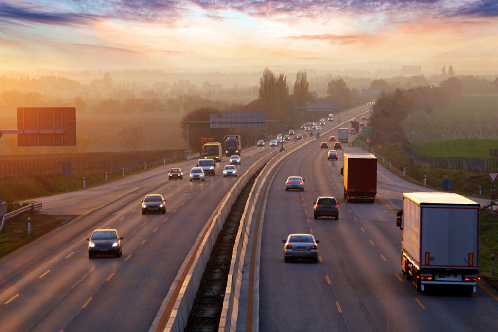Cars driving on a highway at sunset, representing Department of Transportation fuel economy standards.