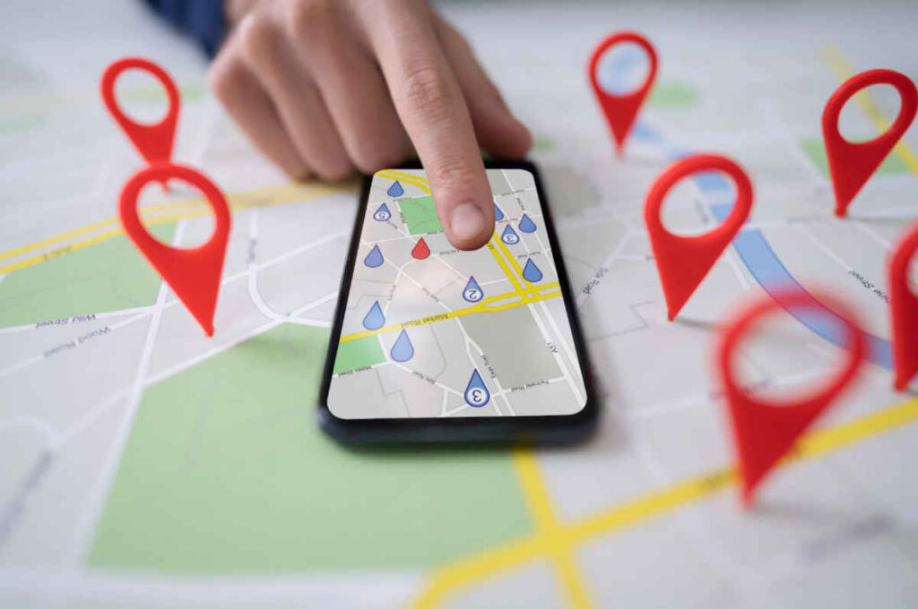 A person uses a map on a smartphone lying on top of a map showing red location markers, representing Google location tracking and privacy law
