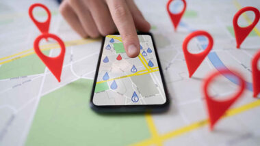 A person uses a map on a smartphone lying on top of a map showing red location markers - Google location tracking