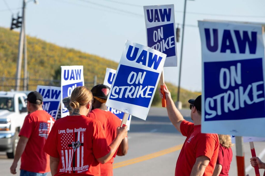 People on strike holding UAW signs, representing the UAW strike.