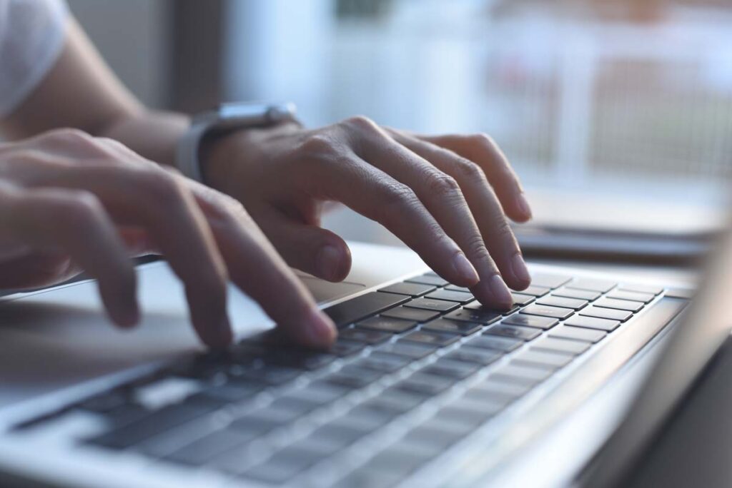 Close up of a womans hands typing on a laptop keyboard, representing the Gershman Investment data breach class action settlement.