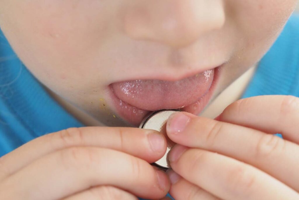 Close up of a child chewing on a coin battery, representing button and coin cell batteries.