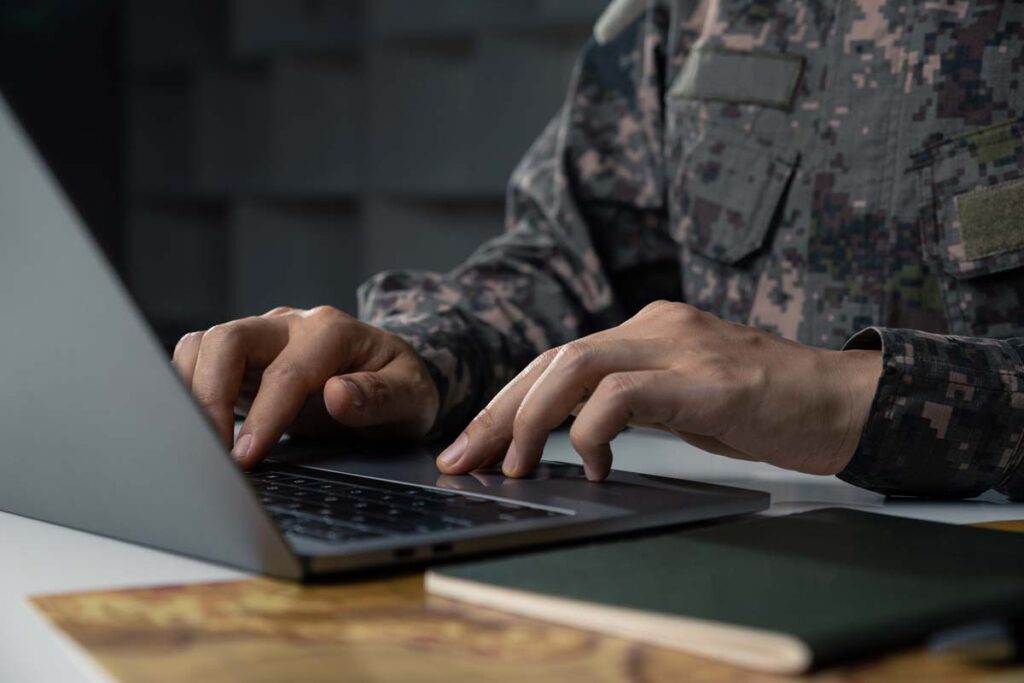 Close up of a person in a military uniform using a laptop, representing the Military.com Facebook privacy class action lawsuit settlement.