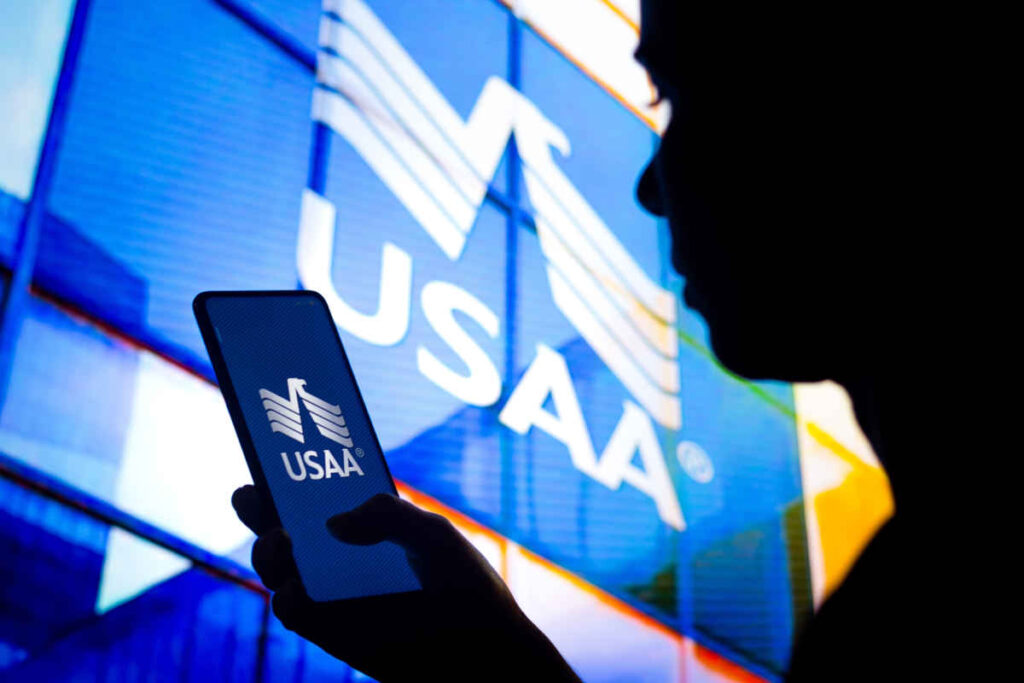 In this photo illustration, a woman's silhouette holds a smartphone with the United Services Automobile Association (USAA) logo representing the USAA data breach class action.