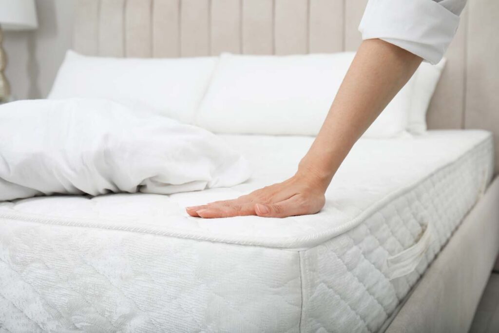 Close up of a womans hand touching a mattress, representing the imported mattresses investigation.