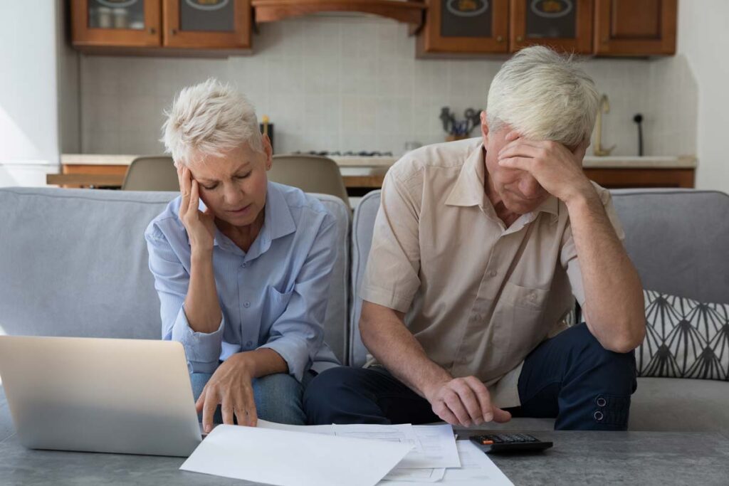 Stressed elderly couple looking at documents, representing the John Hancock class action.