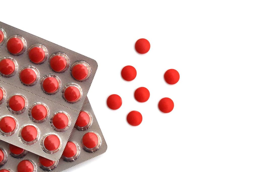 Close up of red medication tablets, representing cold and allergy medicine.