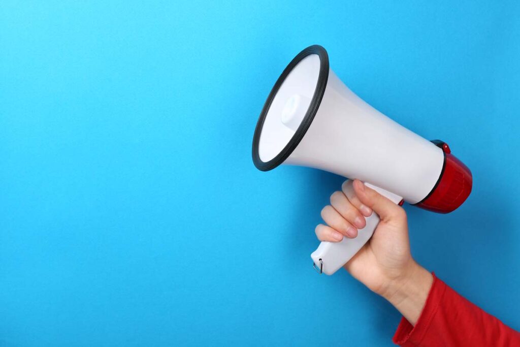 A hand holding a megaphone, against a blue background, representing top recalls for the week of Oct. 9.