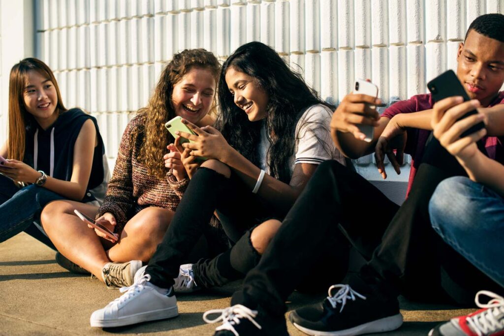 A group of teenagers looking at their smartphones, representing the Not Gonna Lie app.
