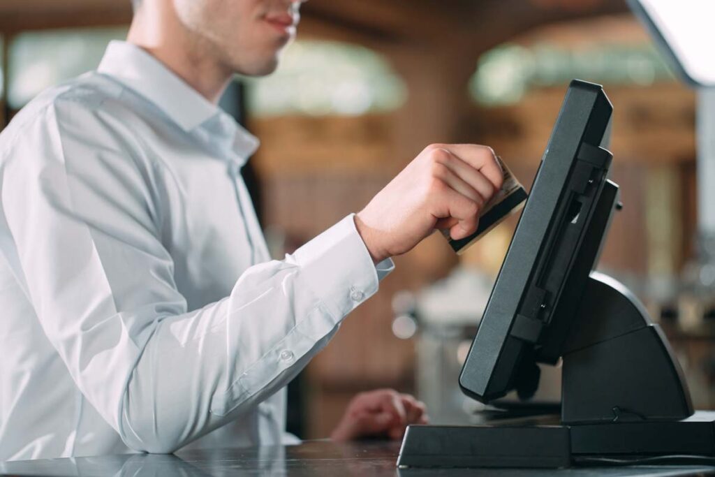 Close up of a waiter charging a card on an ordering system, representing the Earl Enterprises data breach class action lawsuit settlement. Earl Enterprises operates Buca di Beppo and other 