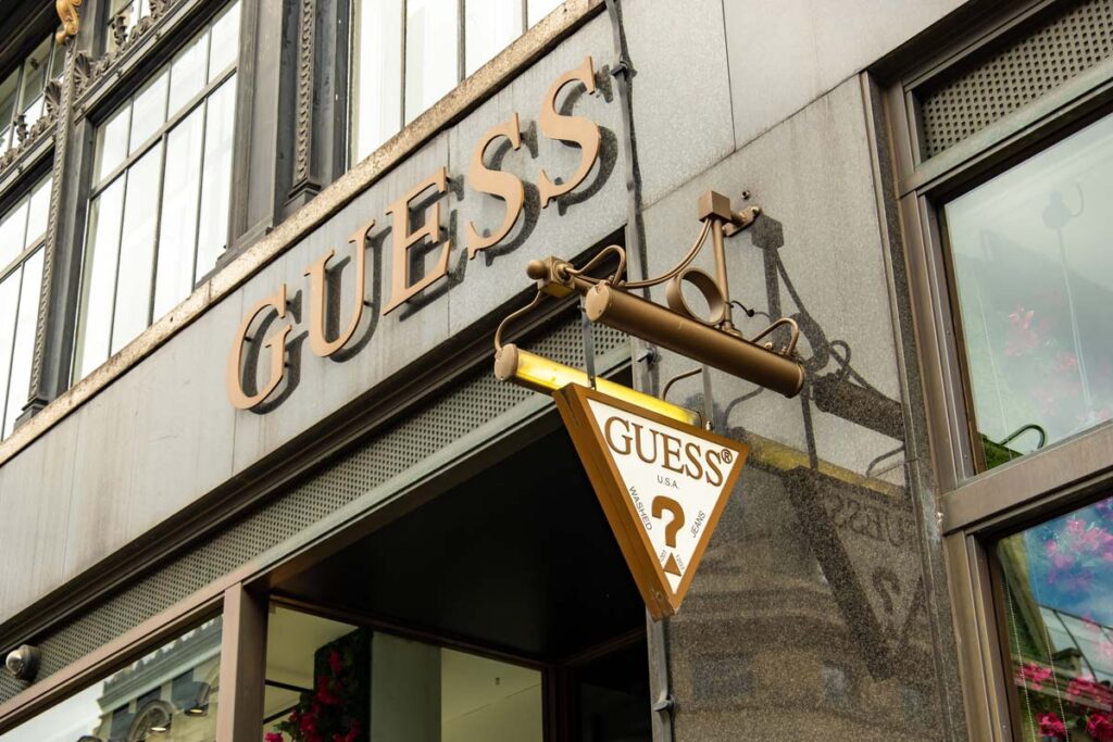 Close up of Guess signage on exterior of a store, representing the Guess sexual harassment lawsuit.