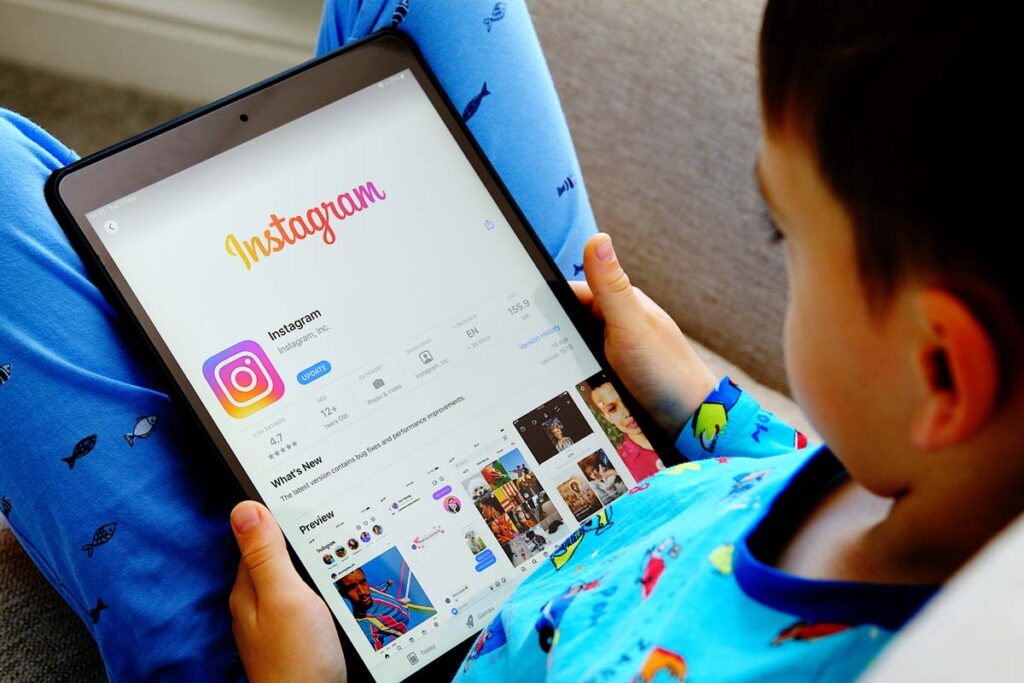 A young boy using a tablet with the Instagram app download page displayed, representing the Meta kids lawsuit.