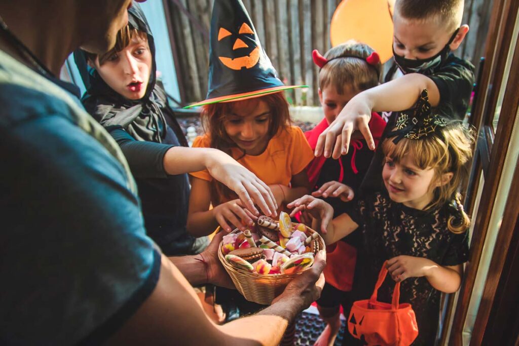 A group of kids in costumes grabbing candy from a bowl, representing Halloween candy spending.