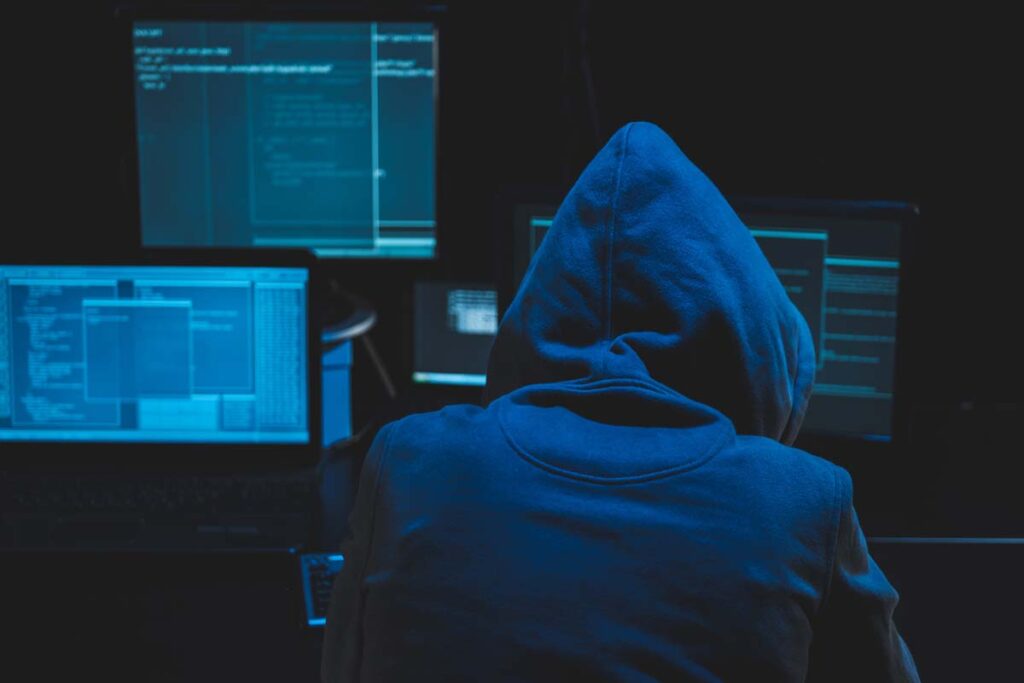 A hooded hacker in front of a computer hacking a system, representing the Inline Network Integration data breach class action lawsuit settlement.